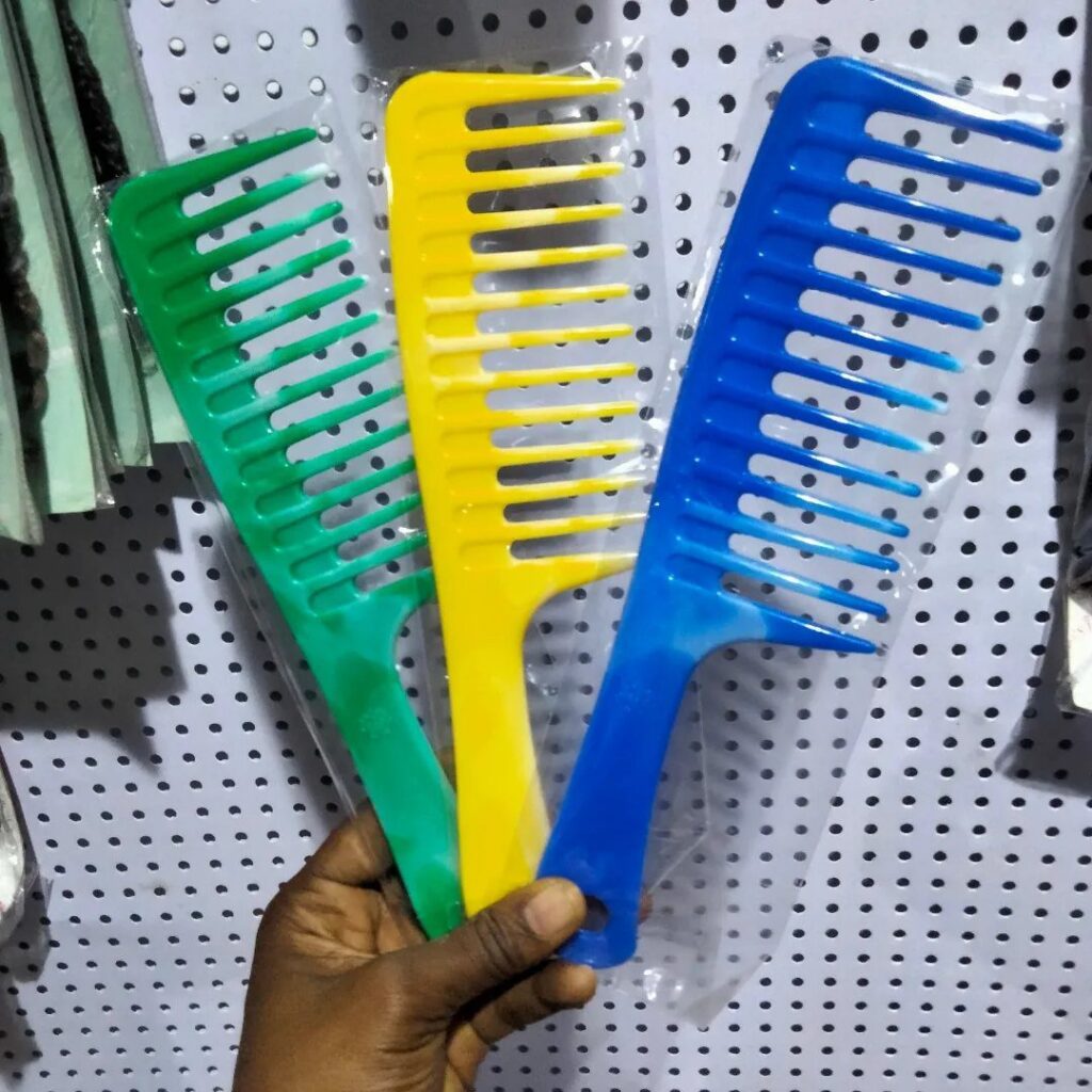 Three colorful wide-tooth combs in green, yellow, and blue held by a hand.