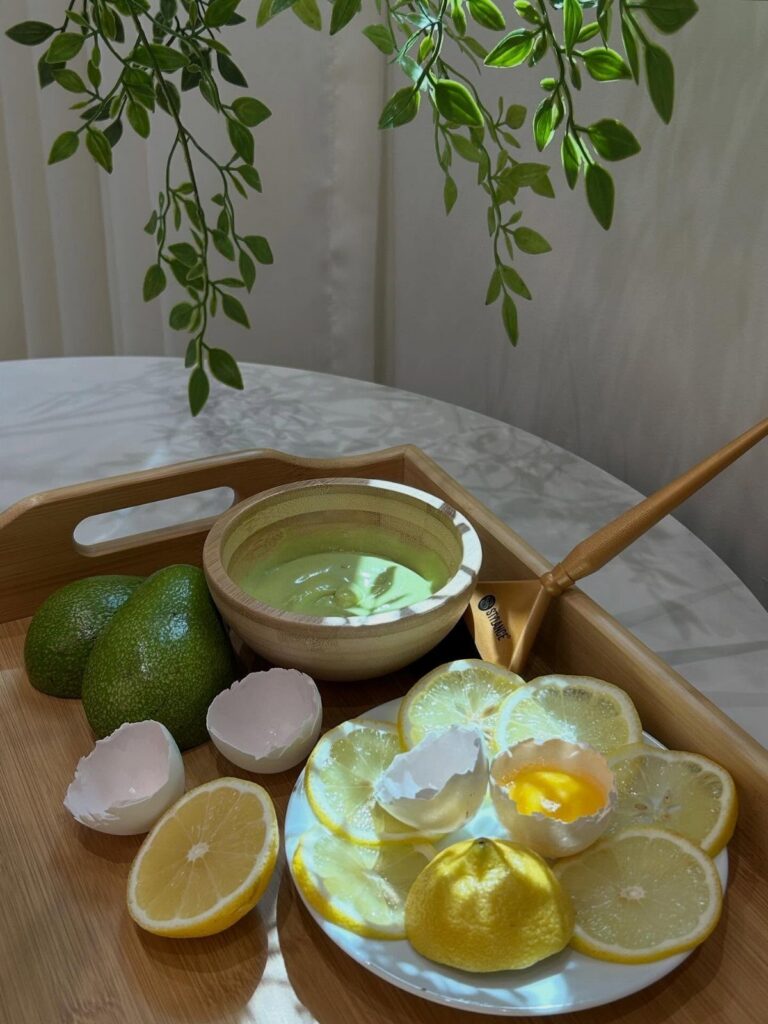 Bowl of green hair mask with avocados, lemons, and eggs on a tray.